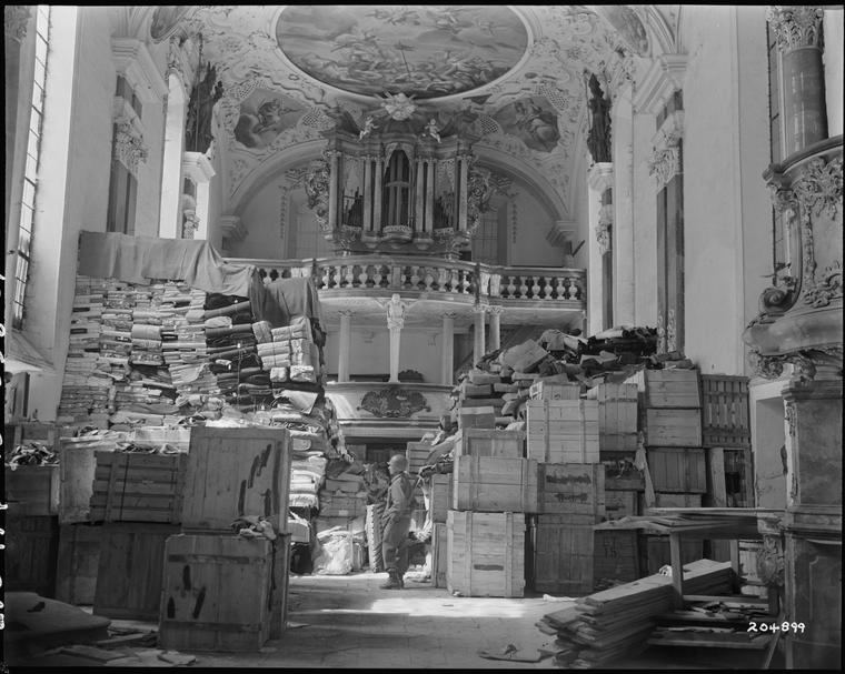 Soldado estadounidense inspecciona botín alemán almacenado en una iglesia en Elligen, Alemania, 24/4/1945