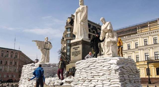 Los voluntarios acumulan sacos de arena para proteger estatuas y monumentos